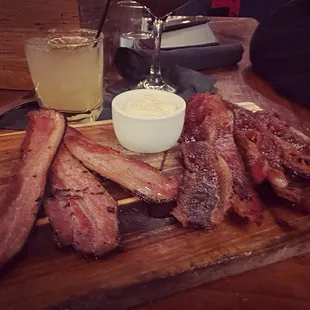 bacon on a cutting board with a glass of beer