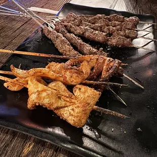 skewers of meat on a black plate