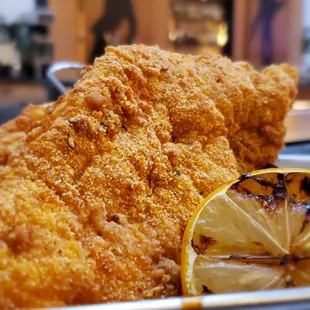 a basket of fried chicken with a lemon wedge