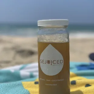 a jar of juice on a beach towel