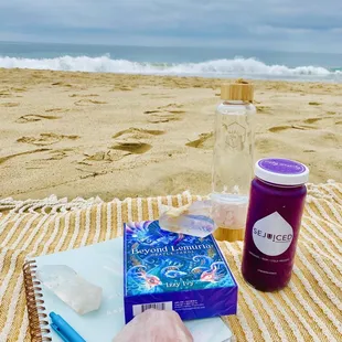 a bottle of sejuice and a notebook on the beach