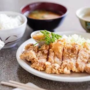 a plate of chicken with rice and chopsticks
