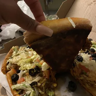 a hand picking up a piece of pizza