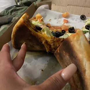 a hand holding a half eaten pizza