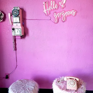 a pink wall with a telephone and a pink chair