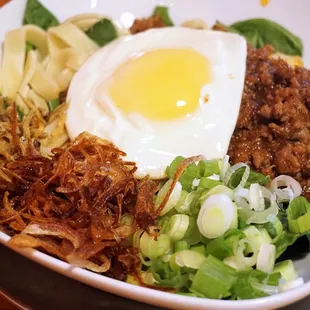 Curry Lamb Pan Mee: pan mee noodles, minced lamb dry-curry, spinach, shallots, green onions, anchovies, toasted coconut, fried egg ($15.95).