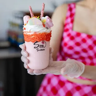 a woman in a pink dress holding a pink and white ice cream sundae