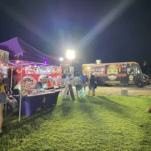 a group of people standing in front of food trucks