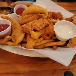 Fish, shrimp, and chips basket. Dipping sauce are tartar sauce and cocktail sauce with a side of lemons.