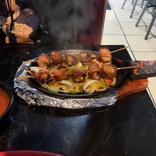 a plate of skewered food and a bowl of soup