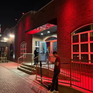 a man standing in front of a red lit building