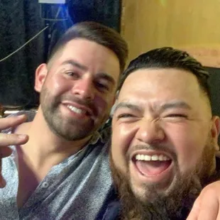 two men smiling and pointing at the camera