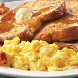 a plate of french toast with bacon and eggs