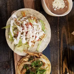 Shredded chicken taco American style and a grilled chicken Mexican style on corn tortilla, refried beans.