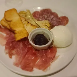 a plate of meats, breads, and condiments