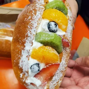 a hand holding a doughnut with fruit on it