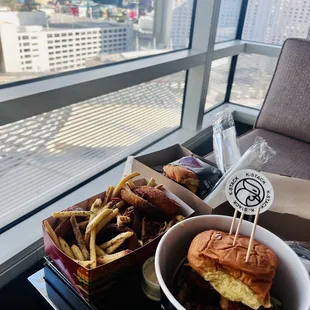 a bowl of fries and a sandwich on a table in front of a window