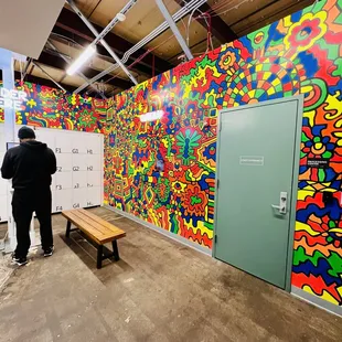 a man standing in front of a colorful mural