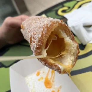 a person holding a pastry with a bite taken out of it