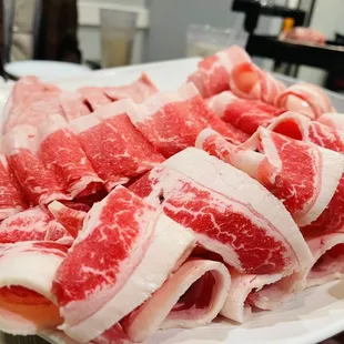a person holding a plate of raw meat