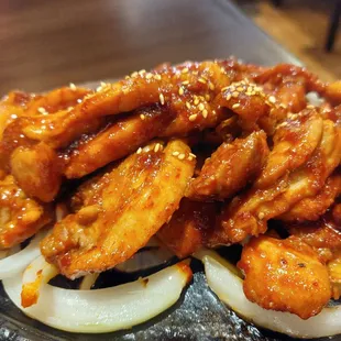 a plate of chicken wings with onions and sesame seeds