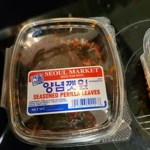 a plastic container of seared perilla leaves