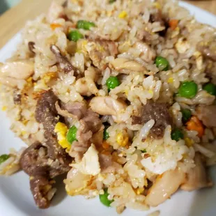 a plate of fried rice with meat and vegetables