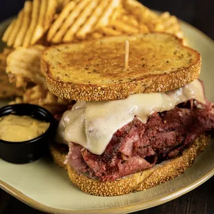 a corned beef sandwich with melted cheese and fries