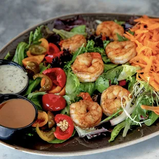 a salad with shrimp, lettuce, tomatoes, peppers, and carrots