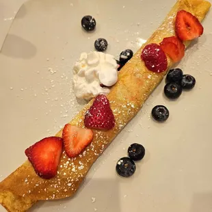 Yummy blintzz filled with ricotta and cream cheese and topped with strawberries, blueberries and powdered sugar