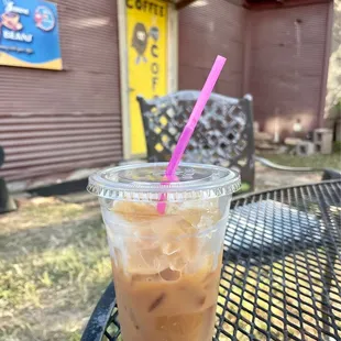 a cup of iced coffee on a table outside