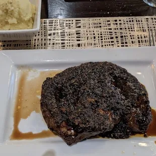 a steak on a plate with a side of mashed potatoes