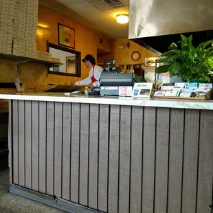 Facing check out counter. Pizza prep on left.