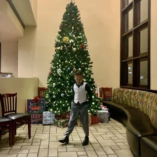 a young boy dancing in front of a christmas tree