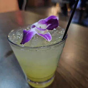 a glass of lemonade with a purple flower