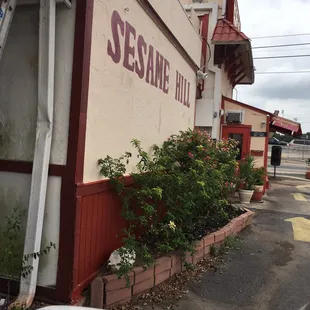 the side of a building with a sign that reads sesame hill
