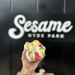  person holding a hot dog in front of a sesame sign
