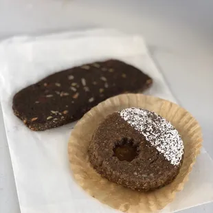 two chocolate donuts with powdered sugar on top