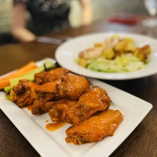 a plate of chicken wings and a plate of vegetables