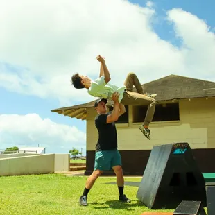 A parkour coach spotting a student doing a wall flip.