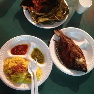 Spicy shrimp in banana leaf at the top. Yellow rice with spicy and mild sauce on the left. Fish on the right.