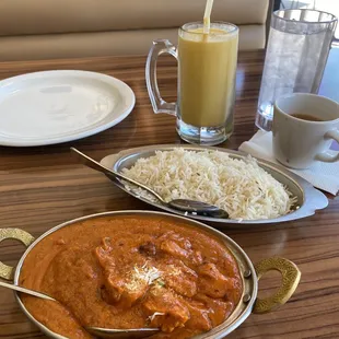 Butter chicken, and mango lassi in the background