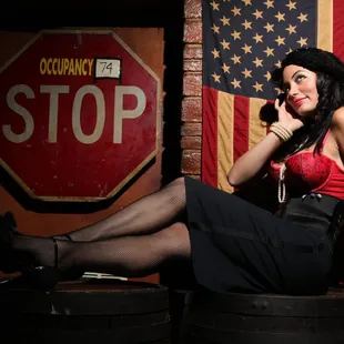 a woman sitting on a barrel talking on a cell phone