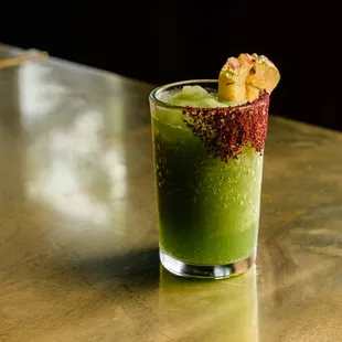 a glass of green drink on a table