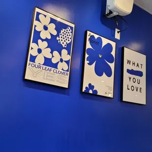 a blue wall with three framed posters on it