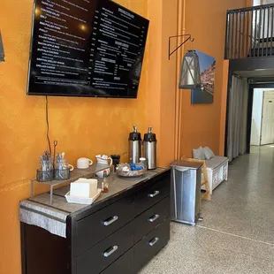 Digital menu above the coffee and utensil station.