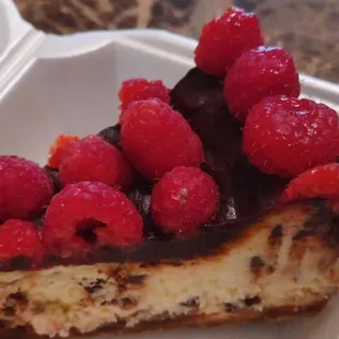 a slice of cheesecake with raspberries on top