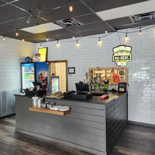 a restaurant counter with lights hanging from the ceiling