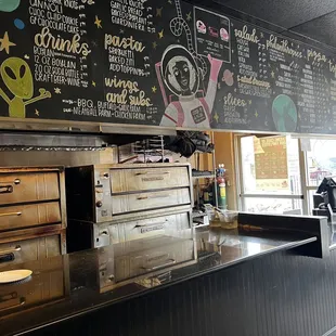 a restaurant counter with a menu on the wall