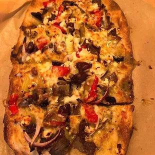 a pizza with olives, peppers, onions, and cheese